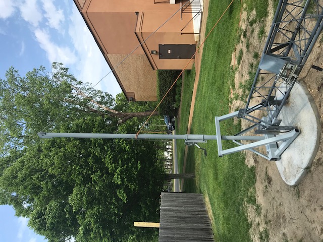 Tall flagpole with an American flag in a backyard near a house.