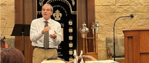 Man speaking in front of synagogue altar.