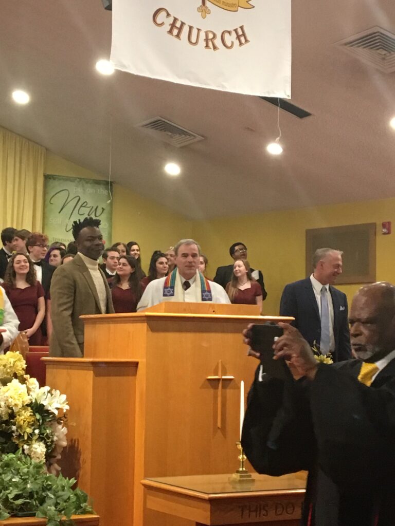 A preacher speaks passionately at a church service with choir and congregation.