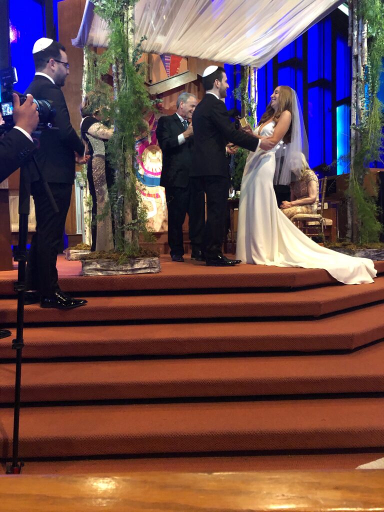 A couple exchanging vows during a wedding ceremony on stage.