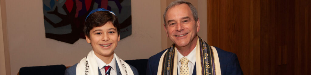A boy and a man celebrating a Jewish ceremony with Torah scrolls.
