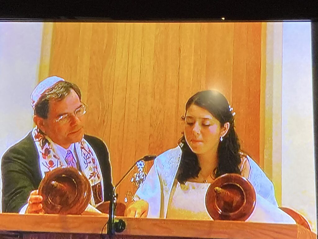A man and woman wearing traditional Jewish prayer shawls at a synagogue.