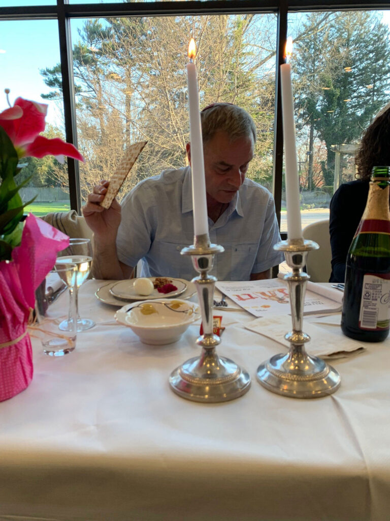 Man enjoying a meal at a candlelit table with flowers and wine.