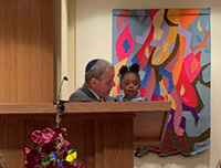 An older man and a young child sharing a moment by a podium.