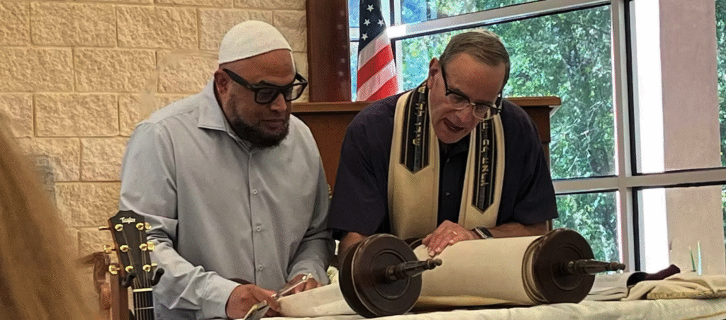 Two men examining a Torah scroll in a synagogue setting.