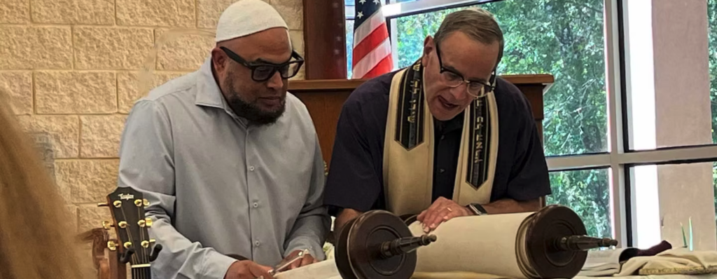 Two men examining a Torah scroll in a synagogue setting.