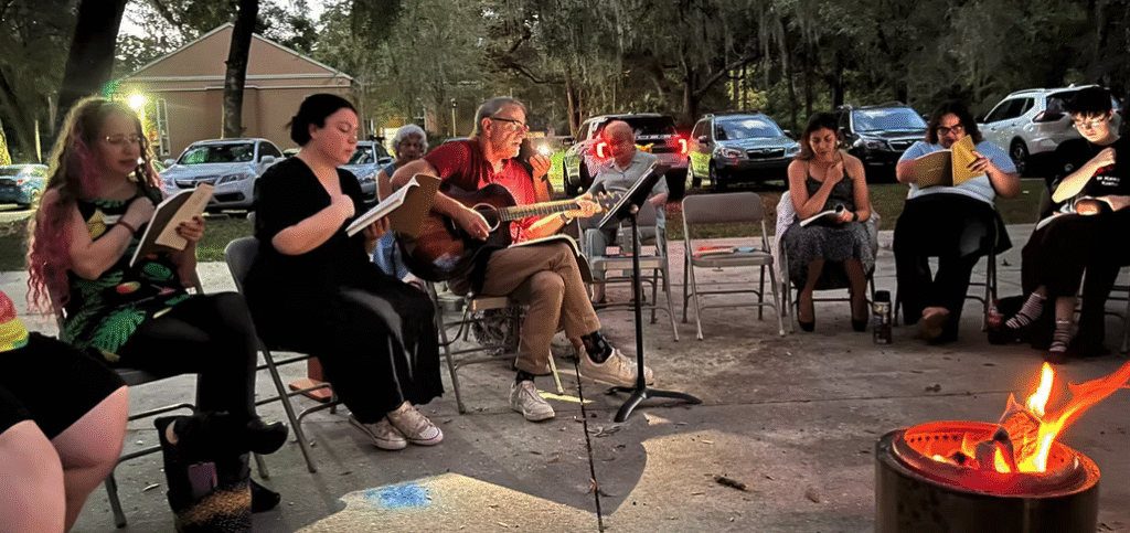 Group of musicians playing outdoors around a campfire.