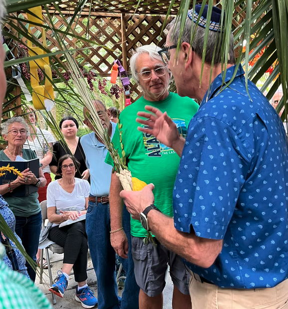 Two men engaging in a conversation during an outdoor event with people around.
