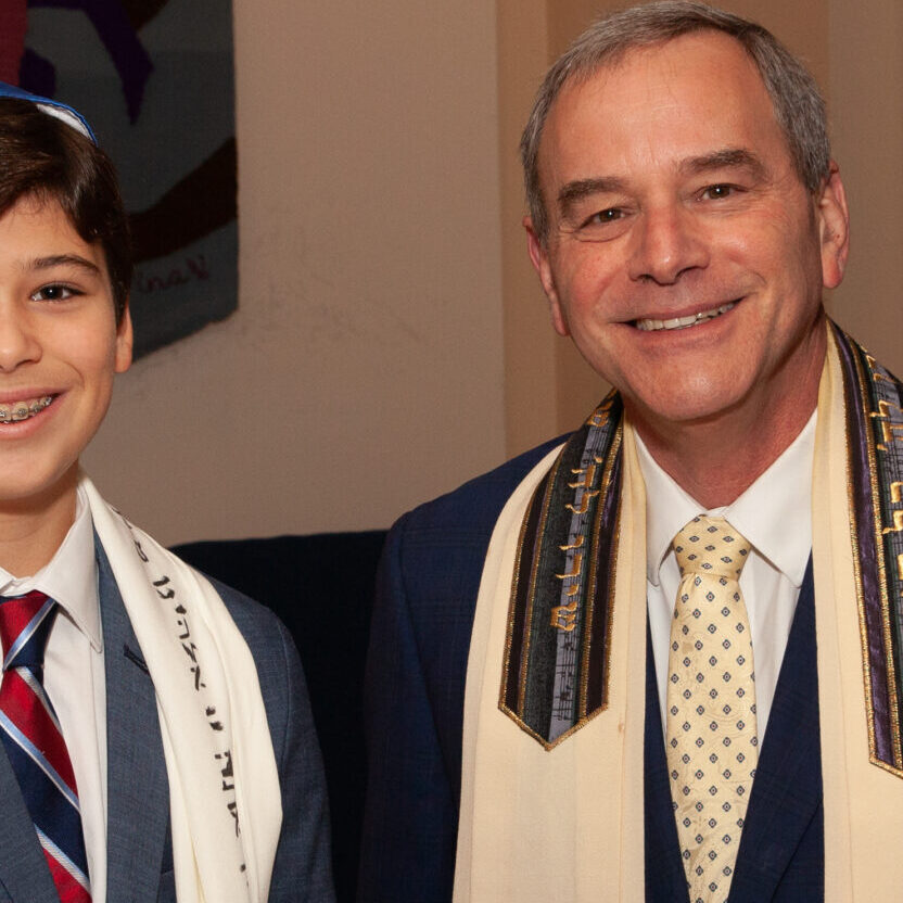 A boy and a man celebrating a Jewish ceremony with Torah scrolls.