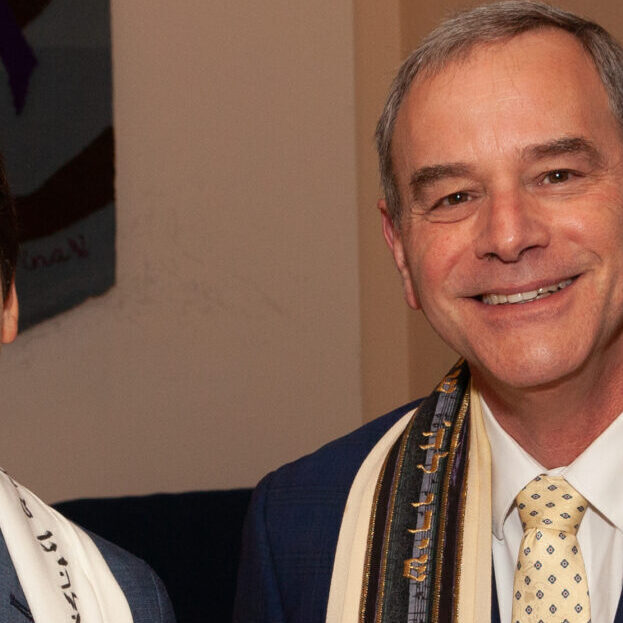 A boy and a man celebrating a Jewish ceremony with Torah scrolls.