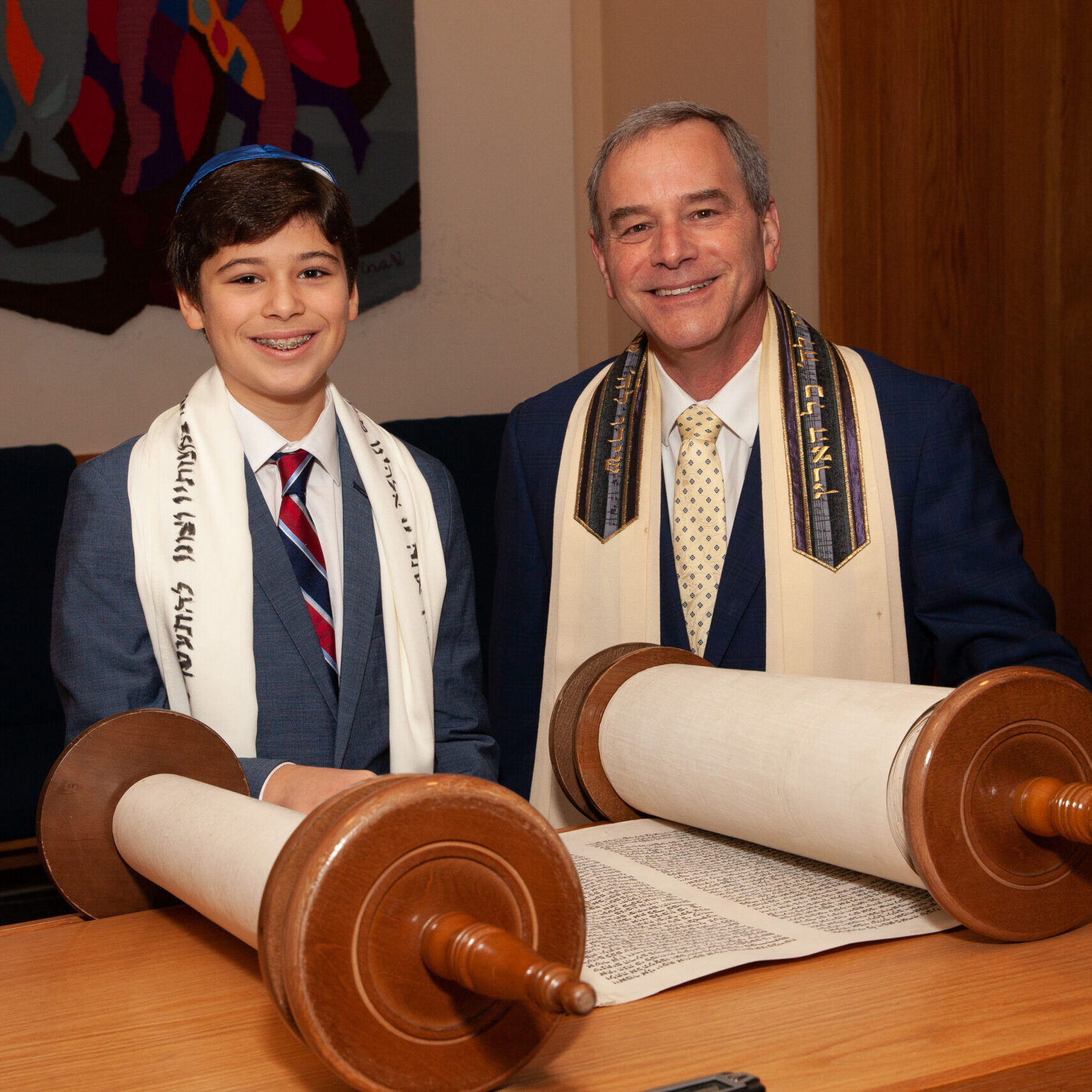 A boy and a man celebrating a Jewish ceremony with Torah scrolls.
