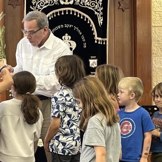 Man reading to a group of children in a cozy room.