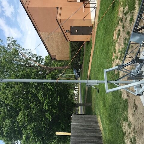 Tall flagpole with an American flag in a backyard near a house.