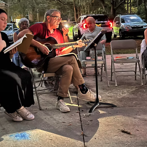 People enjoying an outdoor music session around a fire pit.