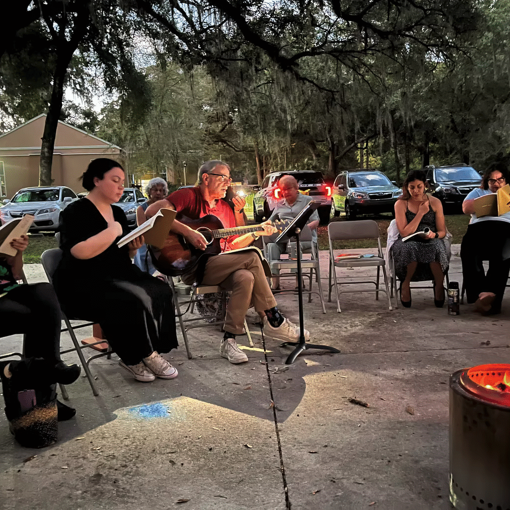 People enjoying an outdoor music session around a fire pit.