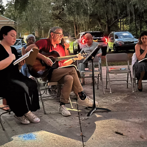 Group of musicians playing outdoors around a campfire.