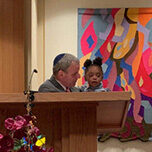 An older man and a young child sharing a moment by a podium.