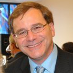Smiling man wearing glasses and a suit.