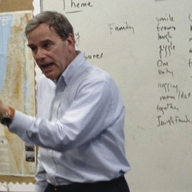 A man passionately teaching in front of a whiteboard.