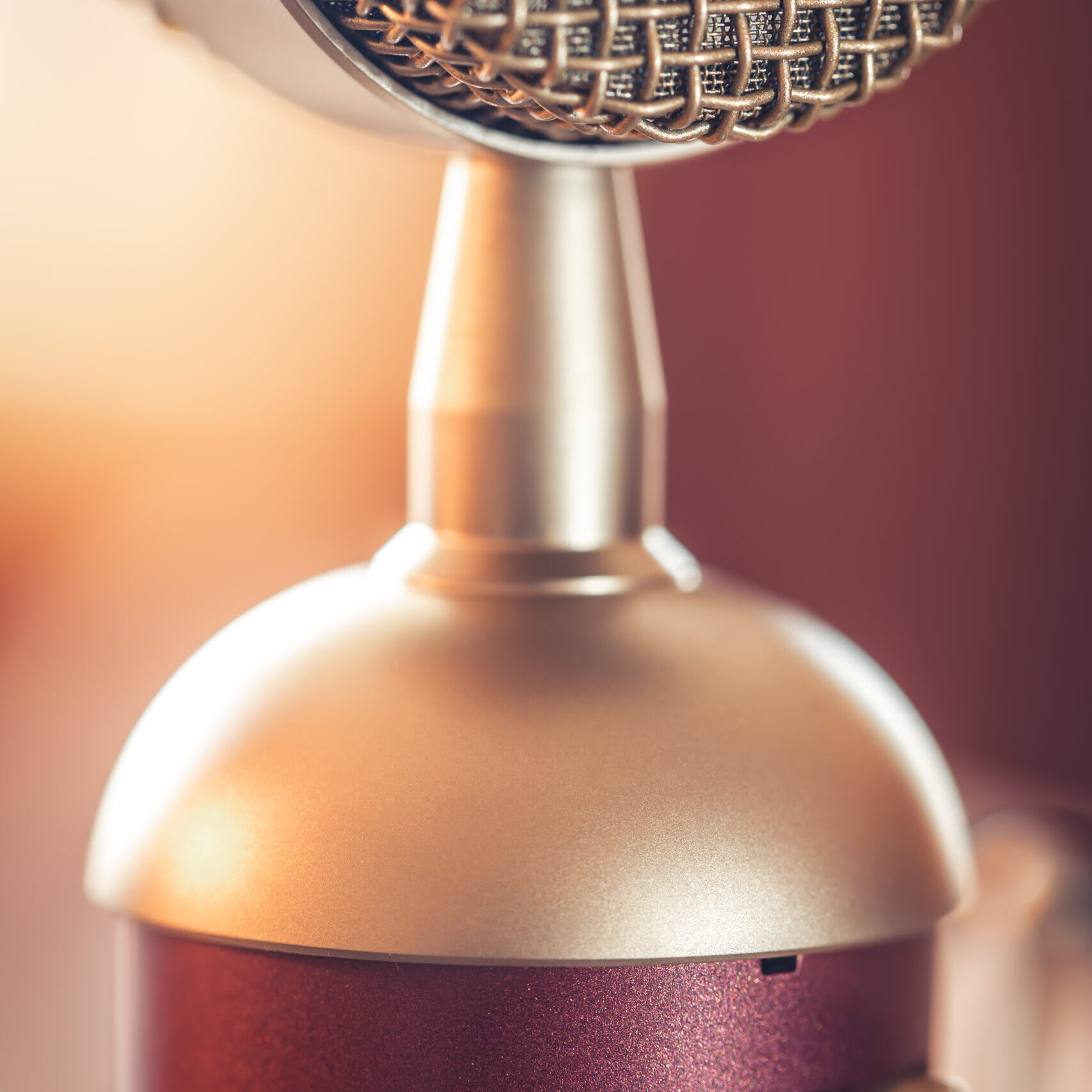 Close-up of a vintage-style microphone with a warm background.