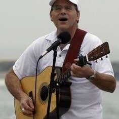 Man singing and playing guitar outdoors.